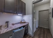 Thumbnail 39 of 49 - a kitchen with a counter top and a door to a laundry room at Century HomePlace, Prattville