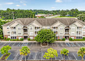 Thumbnail 23 of 31 - A large apartment complex with a parking lot in front.