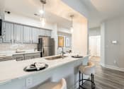 Thumbnail 4 of 31 - A modern kitchen with a bar stool and a fridge.