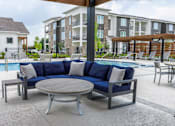 Thumbnail 29 of 36 - A blue sofa with white pillows is in the foreground of a poolside area.