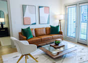 Thumbnail 4 of 36 - A living room with a brown leather couch, a white chair, and two abstract paintings on the wall.