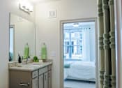 Thumbnail 7 of 36 - A bathroom with a sink, mirror, and a bedroom in the background.