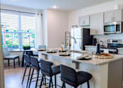 Thumbnail 11 of 36 - A kitchen with a bar area and chairs.