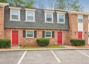 Thumbnail 1 of 29 - a brick apartment building with red doors and a parking lot at Savan Pointe Townhomes East and West, Savannah Georgia