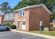 Thumbnail 9 of 29 - a brick apartment building with cars parked in a parking lot at Savan Pointe Townhomes East and West, Savannah