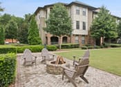 Thumbnail 2 of 22 - an outdoor patio with chairs and a fire pit in front of an apartment building