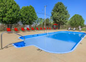 Thumbnail 37 of 53 - a swimming pool with red chairs around it and trees at The Dylan, Murfreesboro, 37129