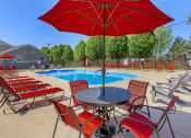Thumbnail 36 of 53 - a pool with red chairs and a table with an umbrella at The Dylan, Murfreesboro, TN 37129