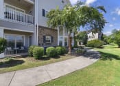 Thumbnail 1 of 49 - a sidewalk in front of a building with trees and bushes
