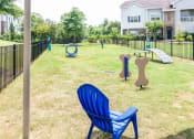Thumbnail 5 of 49 - a park with a playground and a chair in the grass at Century HomePlace, Prattville, AL 36066