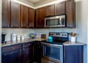 Thumbnail 33 of 49 - a kitchen with stainless steel appliances and wooden cabinets at Century HomePlace, Alabama, 36066