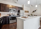 Thumbnail 12 of 48 - A modern kitchen with a white island and stainless steel appliances.at Century Hampton Roads, Suffolk Virginia  