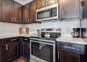 Thumbnail 13 of 48 - A kitchen with dark wood cabinets and a stove top oven.at Century Hampton Roads, Suffolk, VA 23435  