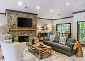 Thumbnail 7 of 24 - A living room with a stone fireplace and a grey couch at Ridge Crossings Apartments, Hoover, 35244