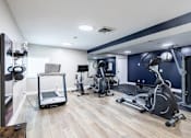 Thumbnail 16 of 18 - A gym with a variety of equipment including treadmills, stationary bikes, and weight machines.