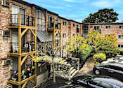 Thumbnail 18 of 18 - A brick building with a balcony and a tree in front.