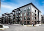 Thumbnail 12 of 58 - A modern apartment building with a curved driveway in front.