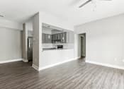 Thumbnail 4 of 14 - A spacious kitchen and living room with wood flooring and white walls.