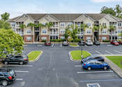 Thumbnail 1 of 18 - A parking lot in front of a building with cars parked.