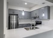 Thumbnail 4 of 18 - A modern kitchen with a stainless steel refrigerator and a white countertop.