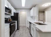 Thumbnail 33 of 49 - an empty kitchen with white cabinets and black appliances  at Peaks at Gainesville, Gainesville, 30507