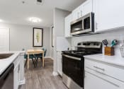 Thumbnail 31 of 49 - a renovated kitchen with white cabinets and black appliances and a dining room table  at Peaks at Gainesville, Gainesville, Georgia