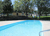 Thumbnail 20 of 30 - A blue swimming pool surrounded by trees and a fence.