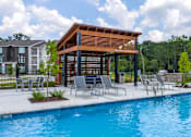 Thumbnail 35 of 36 - A pool area with a wooden pavilion and lounge chairs.