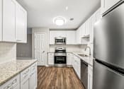 Thumbnail 6 of 20 - A modern kitchen with white cabinets and stainless steel appliances.