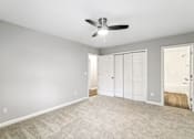 Thumbnail 12 of 20 - A room with a ceiling fan and carpeted floor.