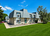 Thumbnail 2 of 22 - A modern house with a grey roof and a green lawn in front.