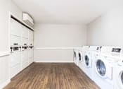 Thumbnail 17 of 18 - A laundry room with a row of washing machines.