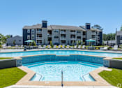 Thumbnail 3 of 40 - A large swimming pool in front of a multi-story apartment building.