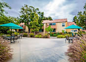 Thumbnail 10 of 18 - a patio with tables and umbrellas in front of a building