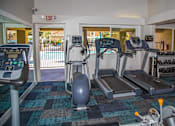 Thumbnail 11 of 18 - a gym with cardio machines and weights in a building with a pool