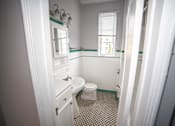 Thumbnail 13 of 13 - A bathroom with a toilet, sink, and mirror.