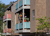 Thumbnail 2 of 26 - a large brown apartment building with green balconies in the daytime and potted plants
