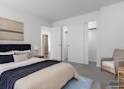 Thumbnail 24 of 26 - A bedroom with a bed, chair, and wardrobe.