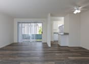 Thumbnail 15 of 26 - an empty living room and kitchen with wood flooring and a ceiling fan