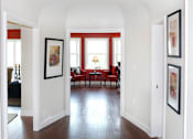 Thumbnail 31 of 39 - Walkway area of an apartment, fitted with wooden walkway, framed pictures on wall, and high ceiling.