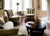 Thumbnail 34 of 39 - Living room area of an apartment, fitted with lounge chairs, a sofa, rug, and coffee table.