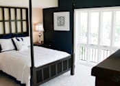 Thumbnail 23 of 39 - Bedroom in an apartment furnished with a queen-size bed, one nightstand, carpet flooring, wide windows, and a high ceiling.