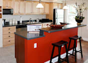 Thumbnail 37 of 39 - Kitchen area of an apartment, fitted with a kitchen island with seating, wood and tiled flooring, and a high ceiling.