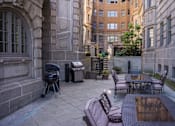 Thumbnail 33 of 39 - Grilling area at Park Lane Villa Apartments fitted with grills, dining tables and chairs, and tiled flooring.