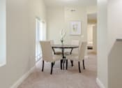 Thumbnail 3 of 39 - Dining room area of an apartment, furnished with a dining table, rug, carpet flooring, and a high ceiling.