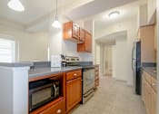 Thumbnail 4 of 39 - Kitchen area of an apartment fitted with stainless steel appliances, spacious cabinets, and tiled flooring at Park Lane Villa.