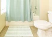 Thumbnail 29 of 39 - Bathroom area of an apartment fitted with tiled flooring, a shower, a toilet, and high ceiling.