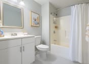 Thumbnail 12 of 15 - a bathroom with a white toilet next to a white bathtub with a shower curtain
