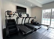 Thumbnail 9 of 16 - A black treadmill and a black stair climber are in a room with a large window.