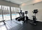 Thumbnail 15 of 16 - A home gym with a treadmill, stationary bike, and rowing machine.